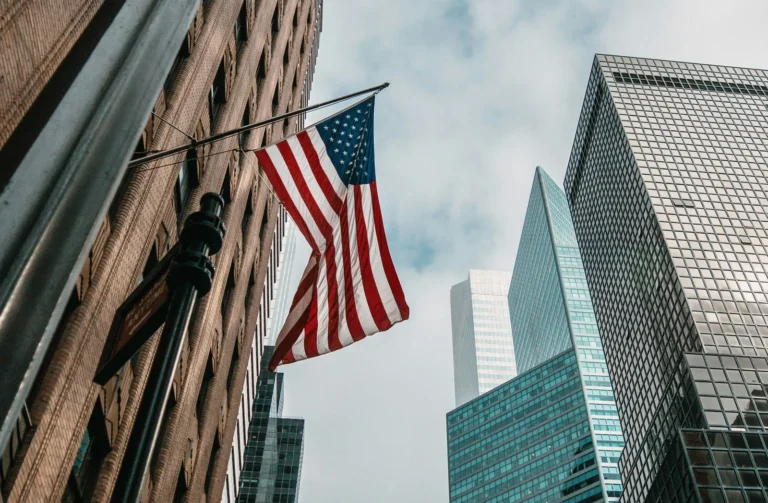 American flag waving in front of New York City skyscrapers, symbolizing top mobile app development companies in the USA