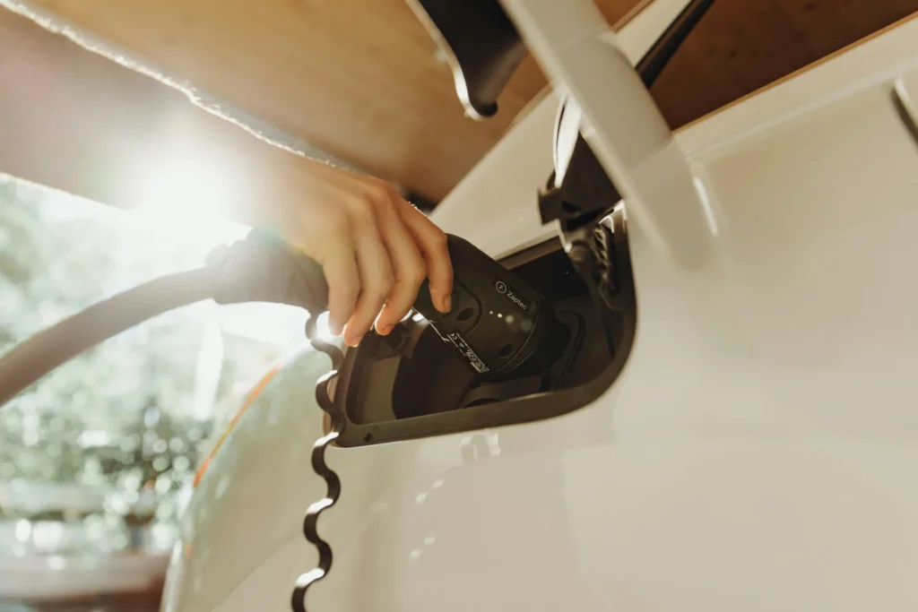 Hand plugging a charging connector into an electric vehicle's charge port, illustrating enterprise EV charging app development