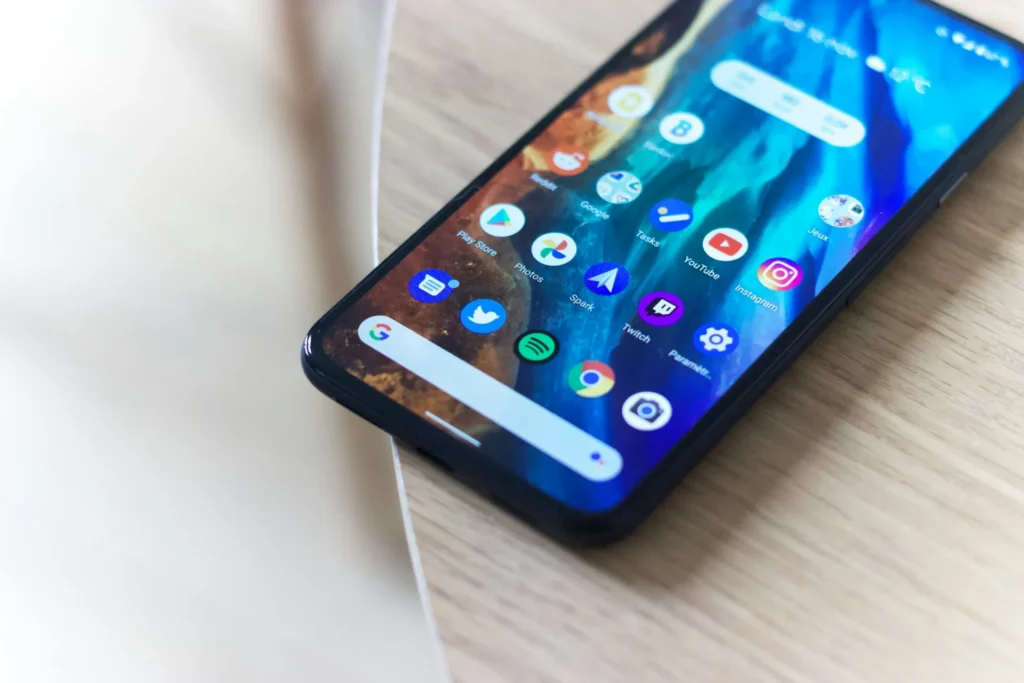 Android smartphone lying on a wooden table with its home screen showing app icons, illustrating Kotlin development companies for enterprise Android apps